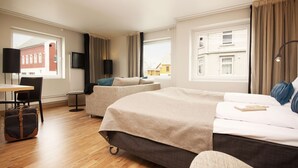 Hotellihuone, jossa on suuri sänky, työpöytä, tuoli, matkalaukku ja televisio.
