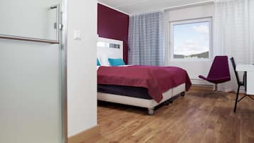 A modern hotel room with a bed, a desk, and a chair.