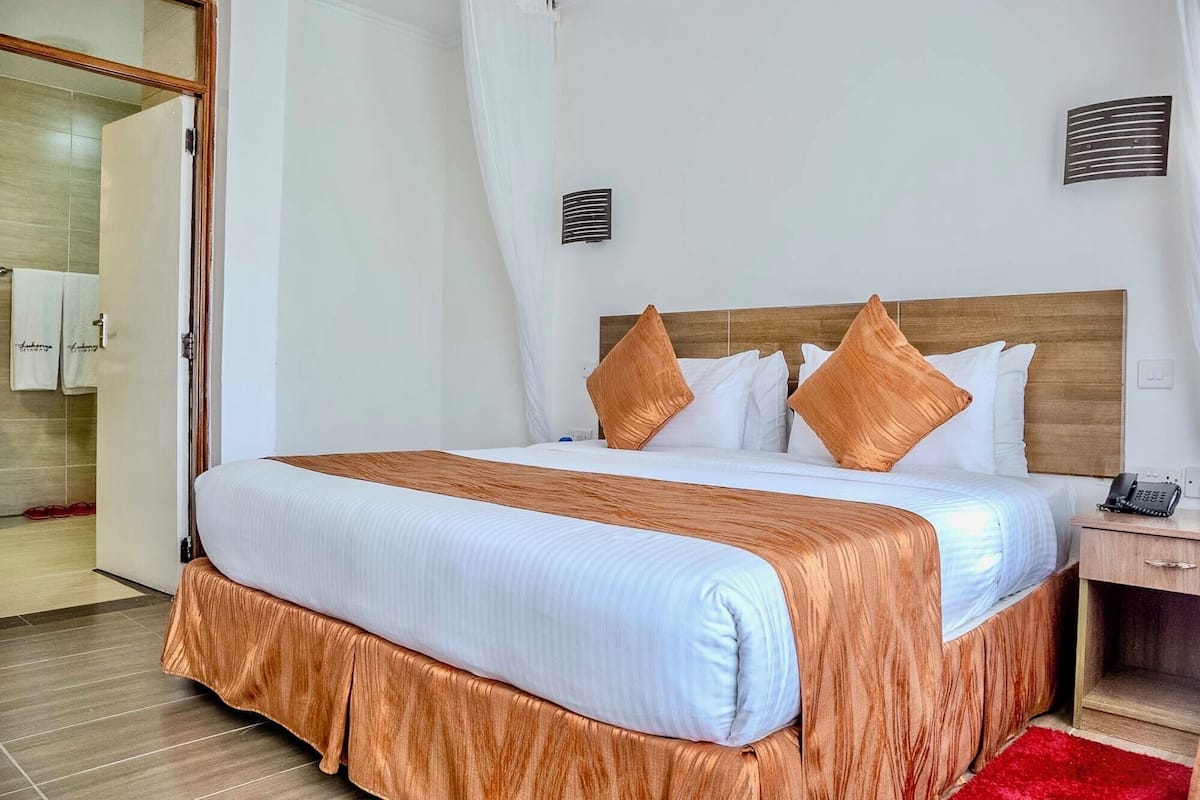 Une chambre d’hôtel avec un grand lit, une tête de lit en bois et une moquette rouge.