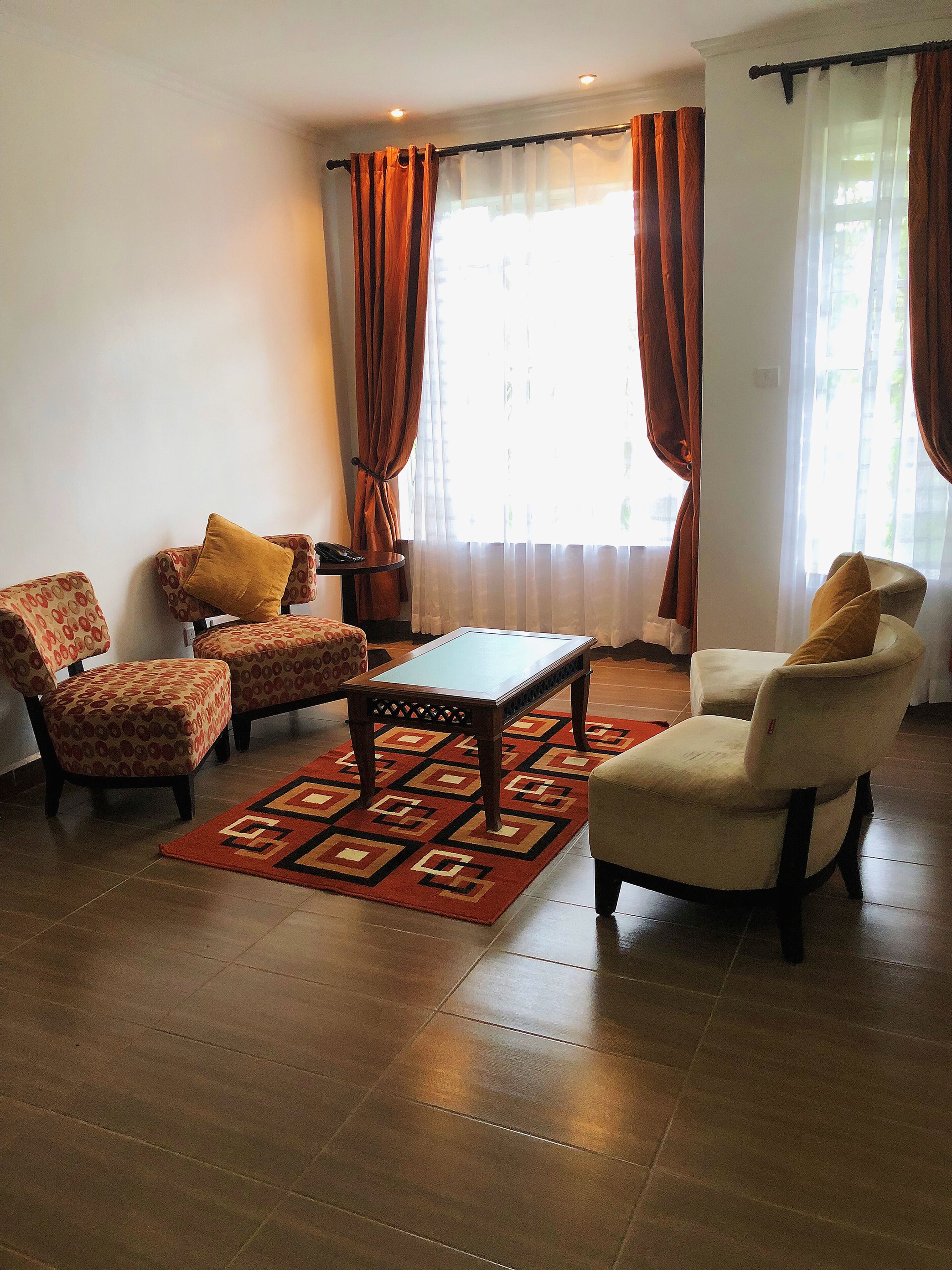 Una sala de estar con sillones estampados, una mesa de centro y una alfombra.