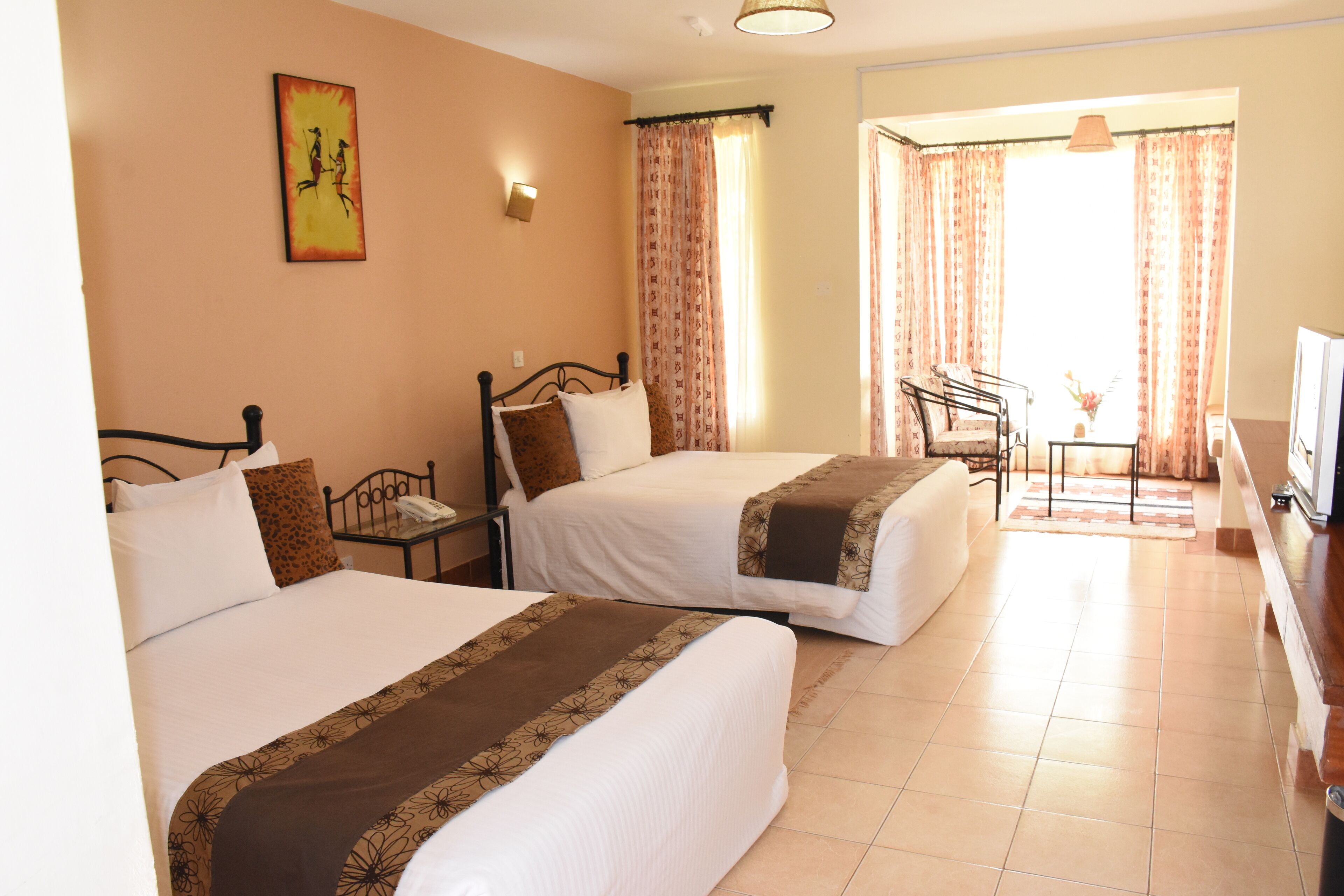 A hotel room with two beds, a desk, a chair, a television, and a window with curtains.