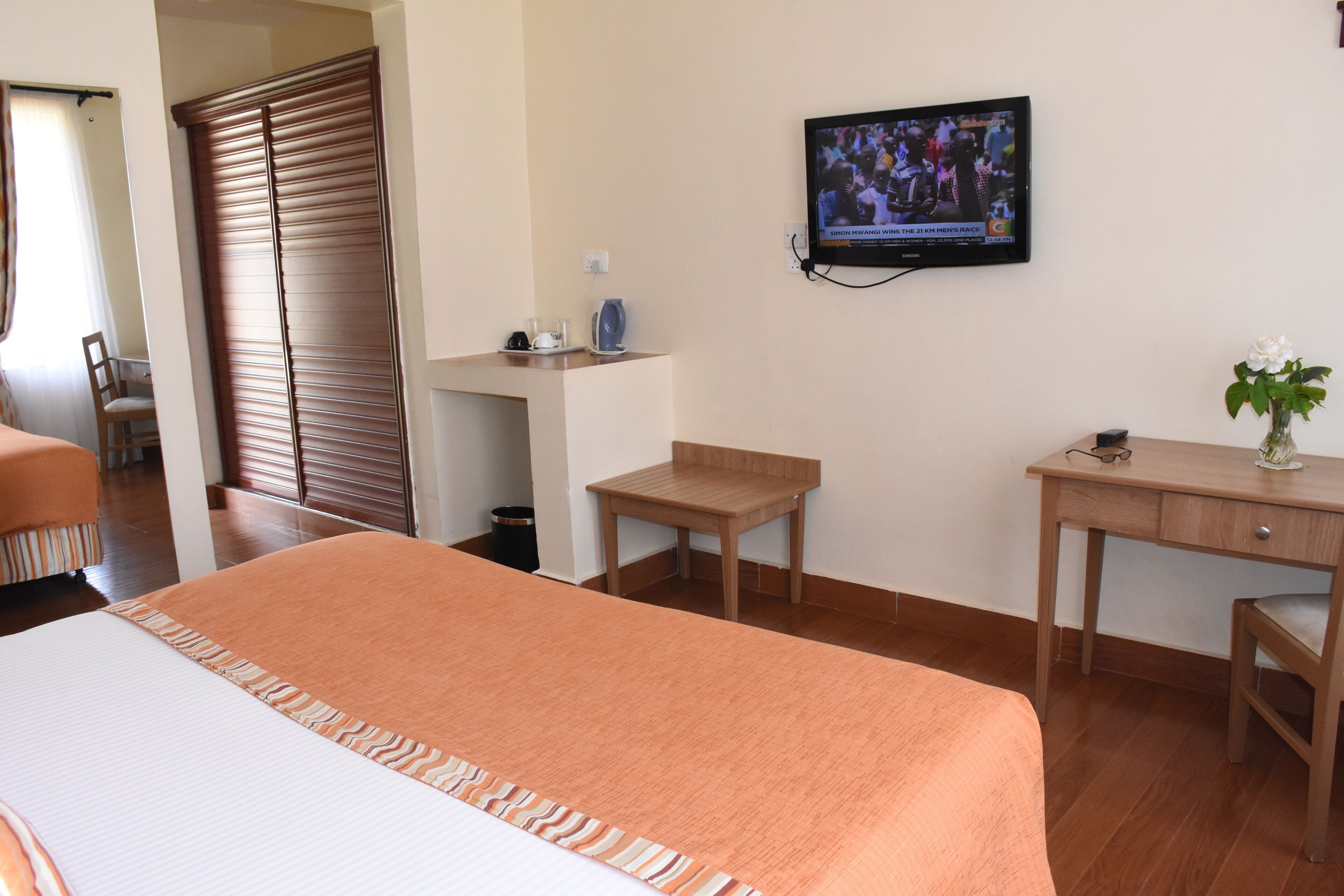 Une chambre d’hôtel avec un lit, un bureau, une chaise, une télévision et une fenêtre.