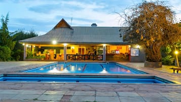 Una piscina al aire libre, sombrillas, sillones reclinables de piscina