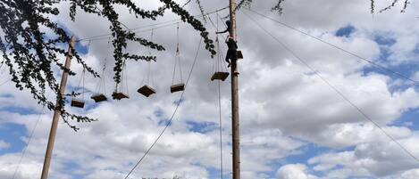 A utility pole with multiple wooden boxes attached to it, surrounded by trees and a partly cloudy sky.