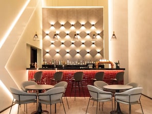 A bar area with a geometric patterned wall, multiple seating arrangements, and a variety of bottles on the bar counter. - ibis Dubai Al Rigga (Dubai)