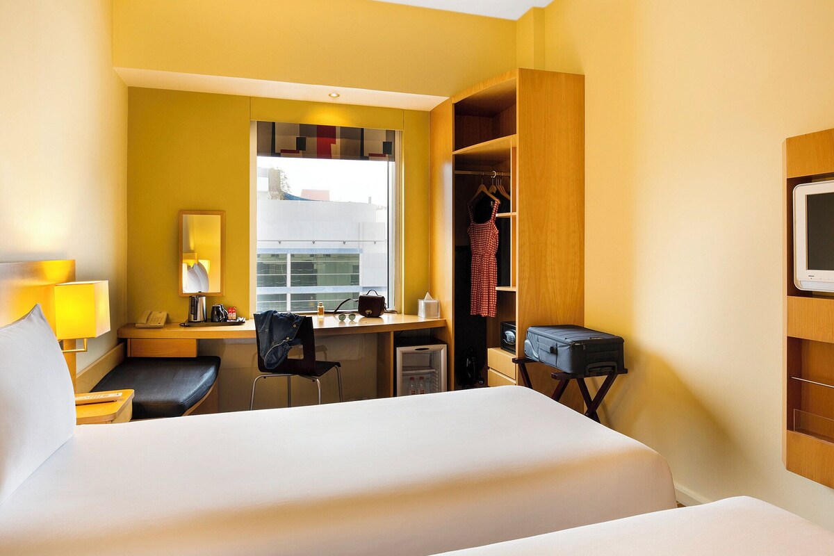 A hotel room with a bed, desk, chair, and wardrobe.