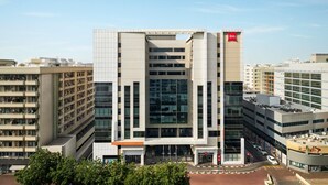A modern hotel with a central atrium, multiple floors, and a prominent 'ibis' logo. - ibis Dubai Al Rigga (Dubai)