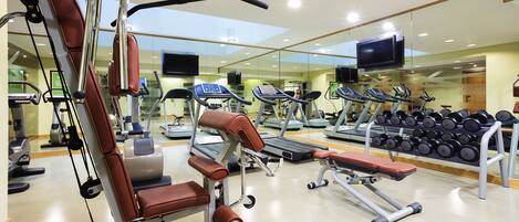 A modern gym with various exercise equipment, including treadmills, dumbbells, and weight machines.