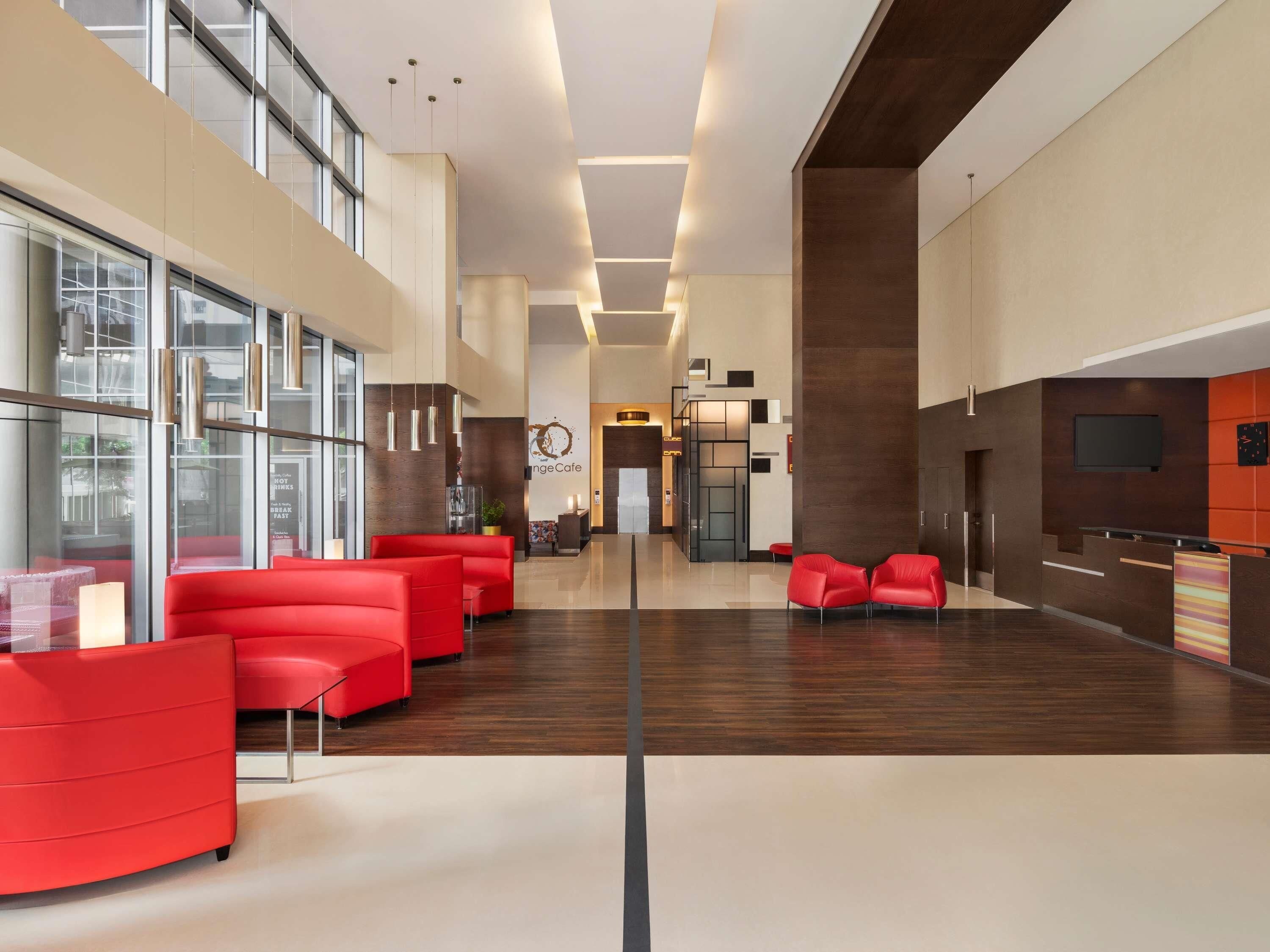 A modern lobby with red seating, a reception desk, and a large window.