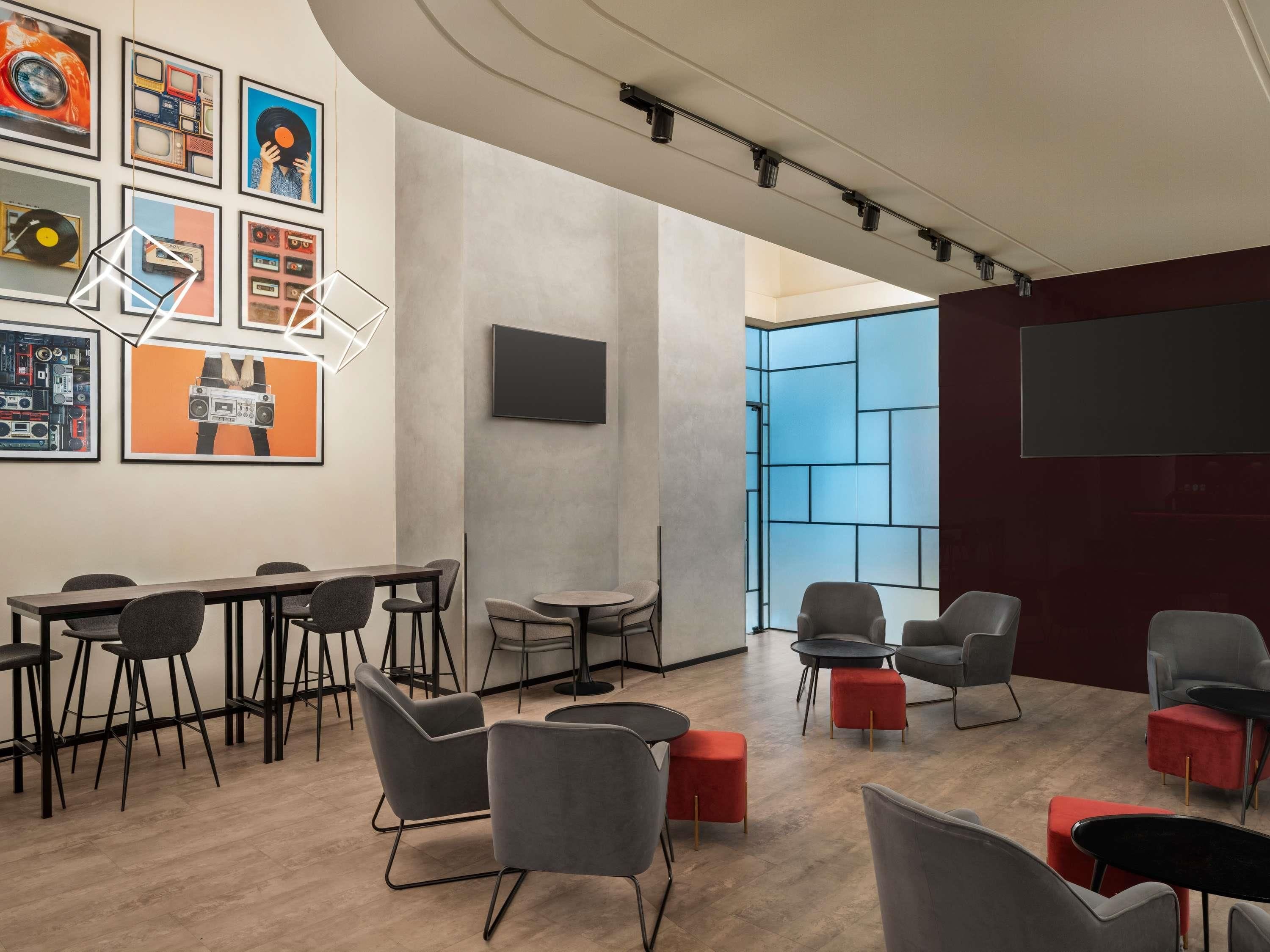 A modern conference room with a long table, multiple chairs, a large screen, and a blue partition wall.