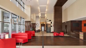 A modern lobby with red seating, a reception desk, and a large window. - ibis Dubai Al Rigga (Dubai)