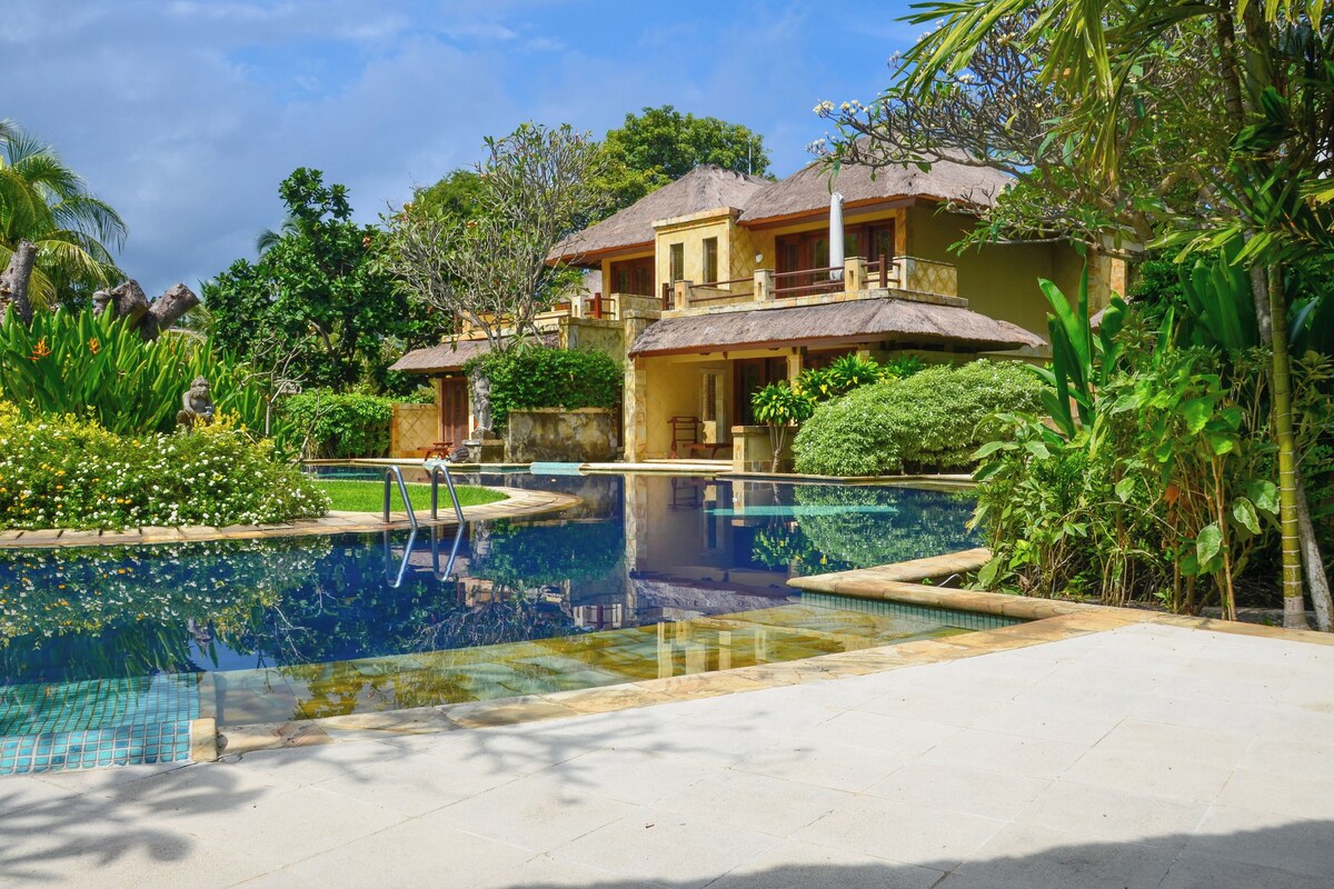 A resort with a swimming pool, lush greenery, and traditional architecture.