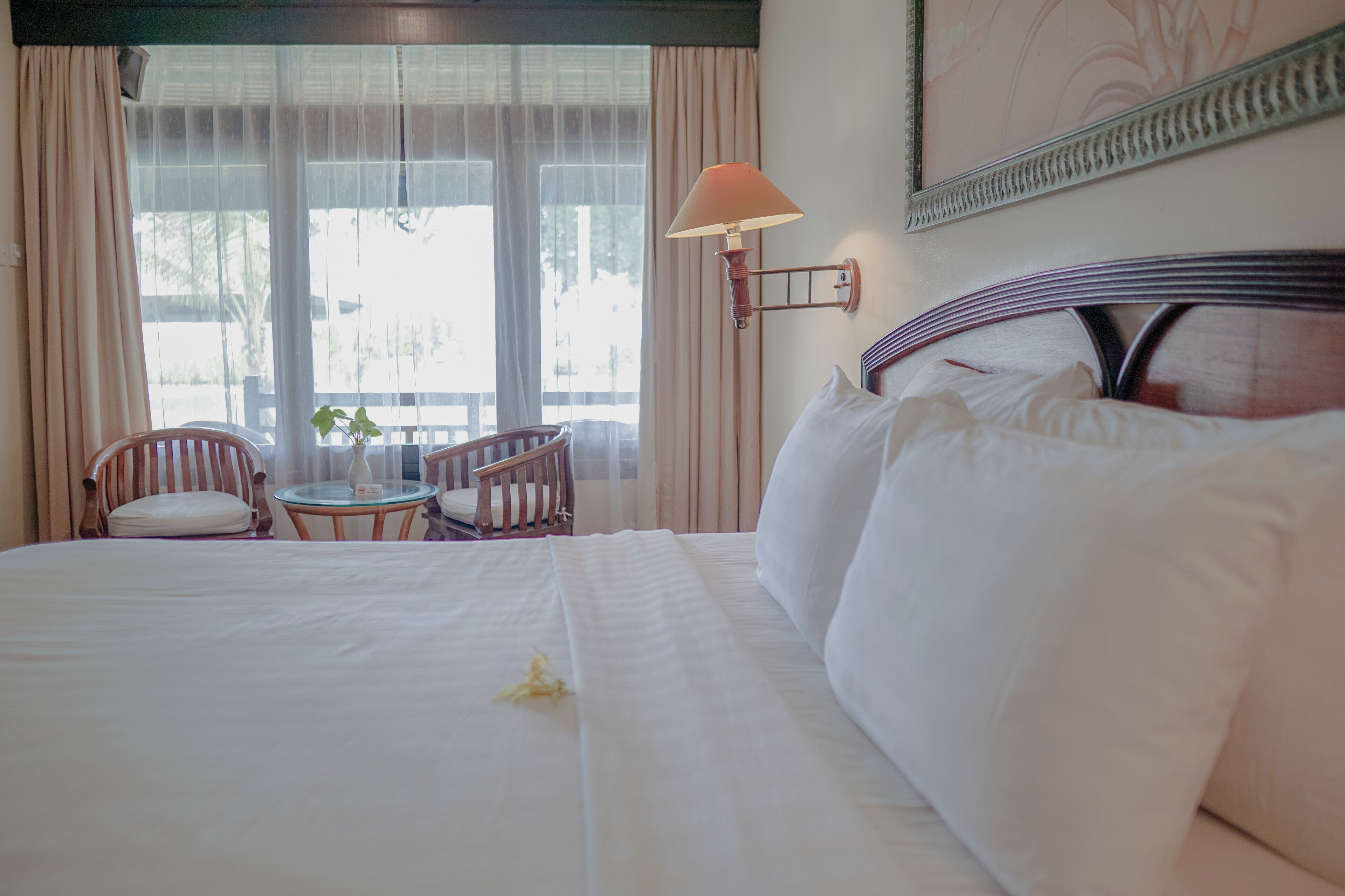 A hotel room with a large bed, a small table, two chairs, and a lamp.