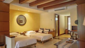 A hotel room with two beds, a wooden headboard, a round mirror, a small table, and a chair.
