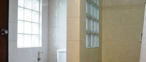 A bathroom with a toilet, a shower, and a window.