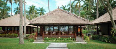 Un resort con cabañas de techo de paja, un camino pavimentado y abundante vegetación.