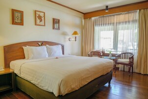 Una camera d'albergo con un letto grande, un comodino, una sedia, un tavolino e una finestra con tende.