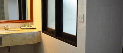 A bathroom with a marble sink, a mirror, and a window with frosted glass.