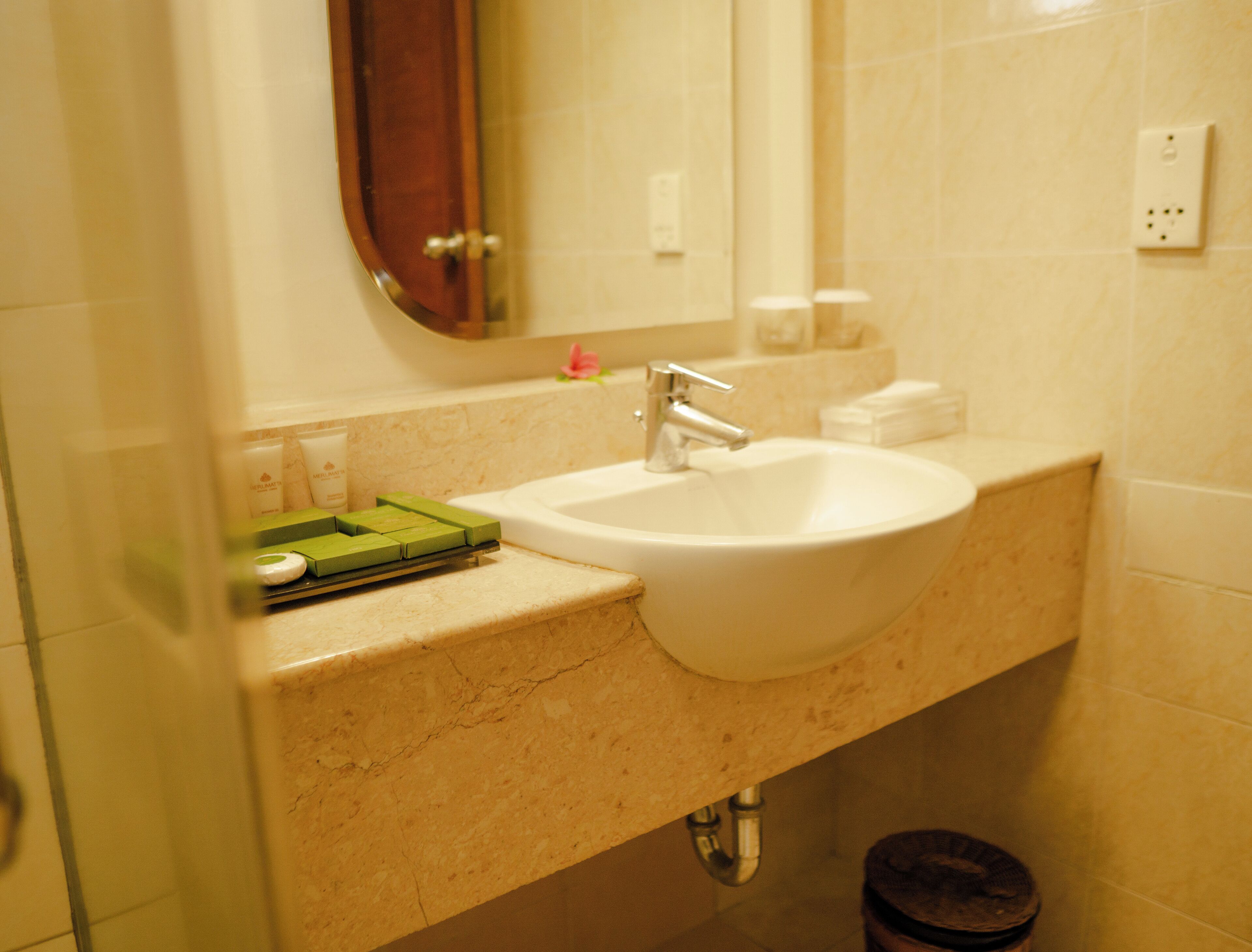 A bathroom with a white sink, a mirror, and a green soap dish.