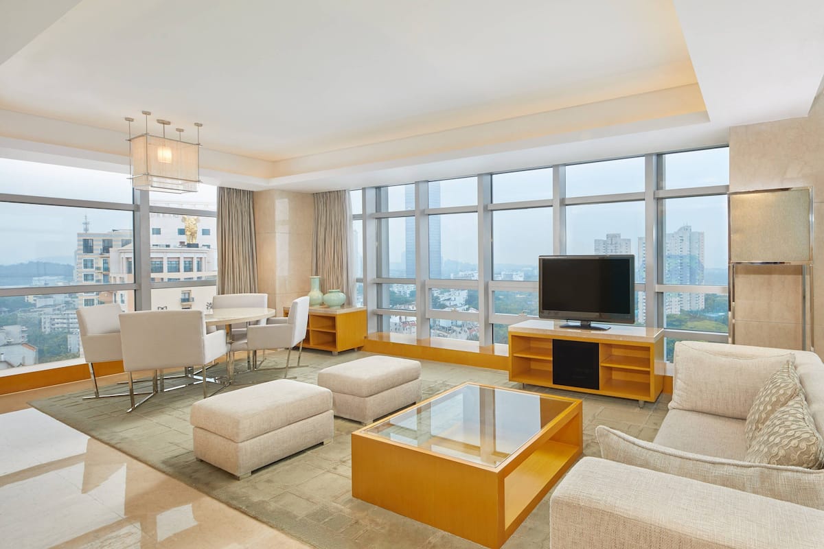A modern living room with a large window, a flat-screen TV, and a sofa.
