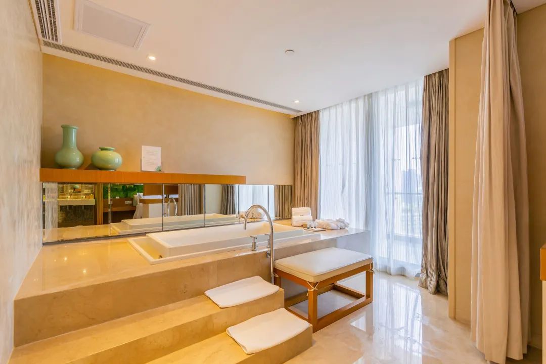 Un baño moderno con un espejo grande, una bañera y un tocador con lavabo.