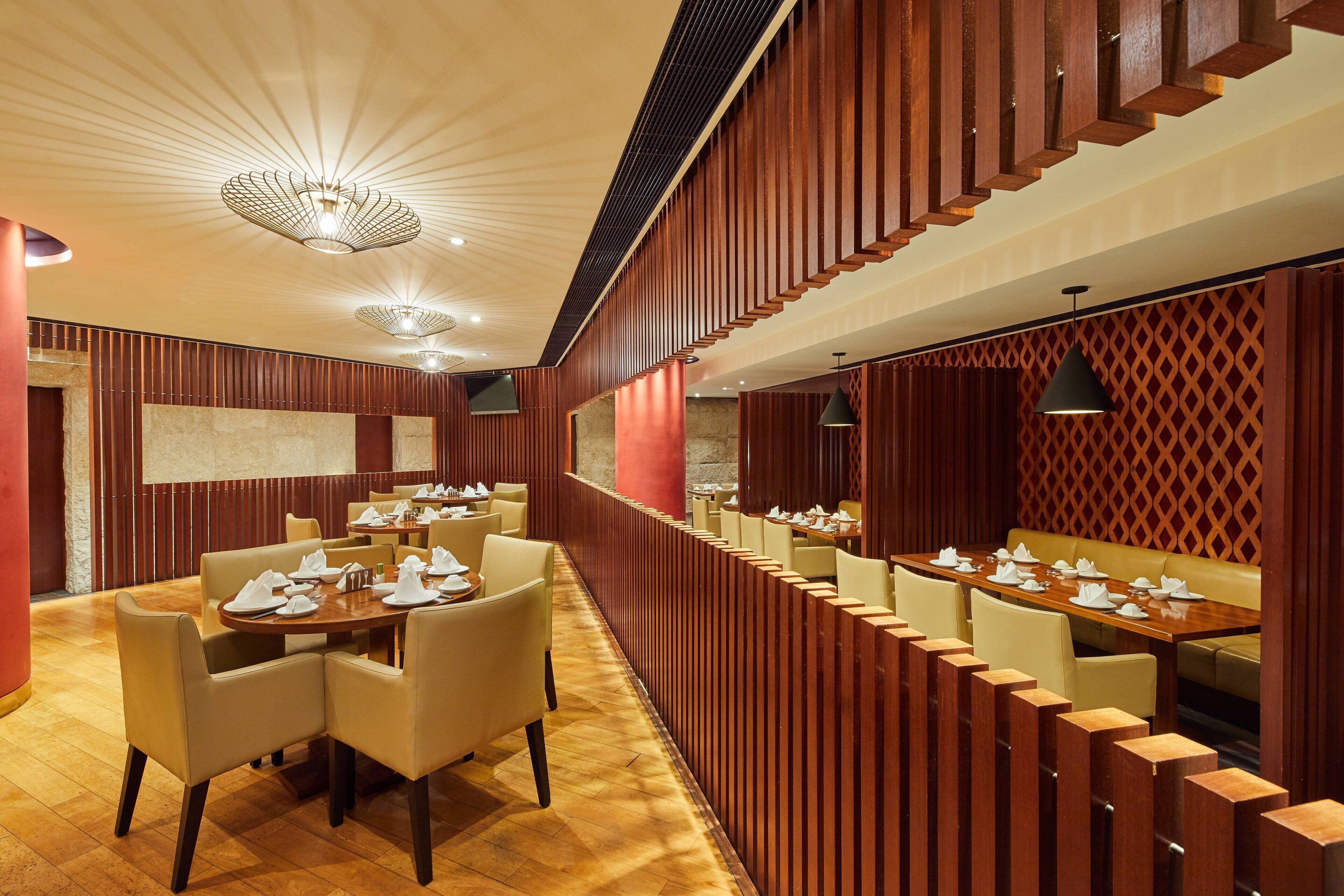 Un restaurant avec des murs lambrés, des tables rondes et des chaises.