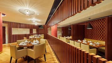 Un restaurant avec des murs lambrés, des tables rondes et des chaises.