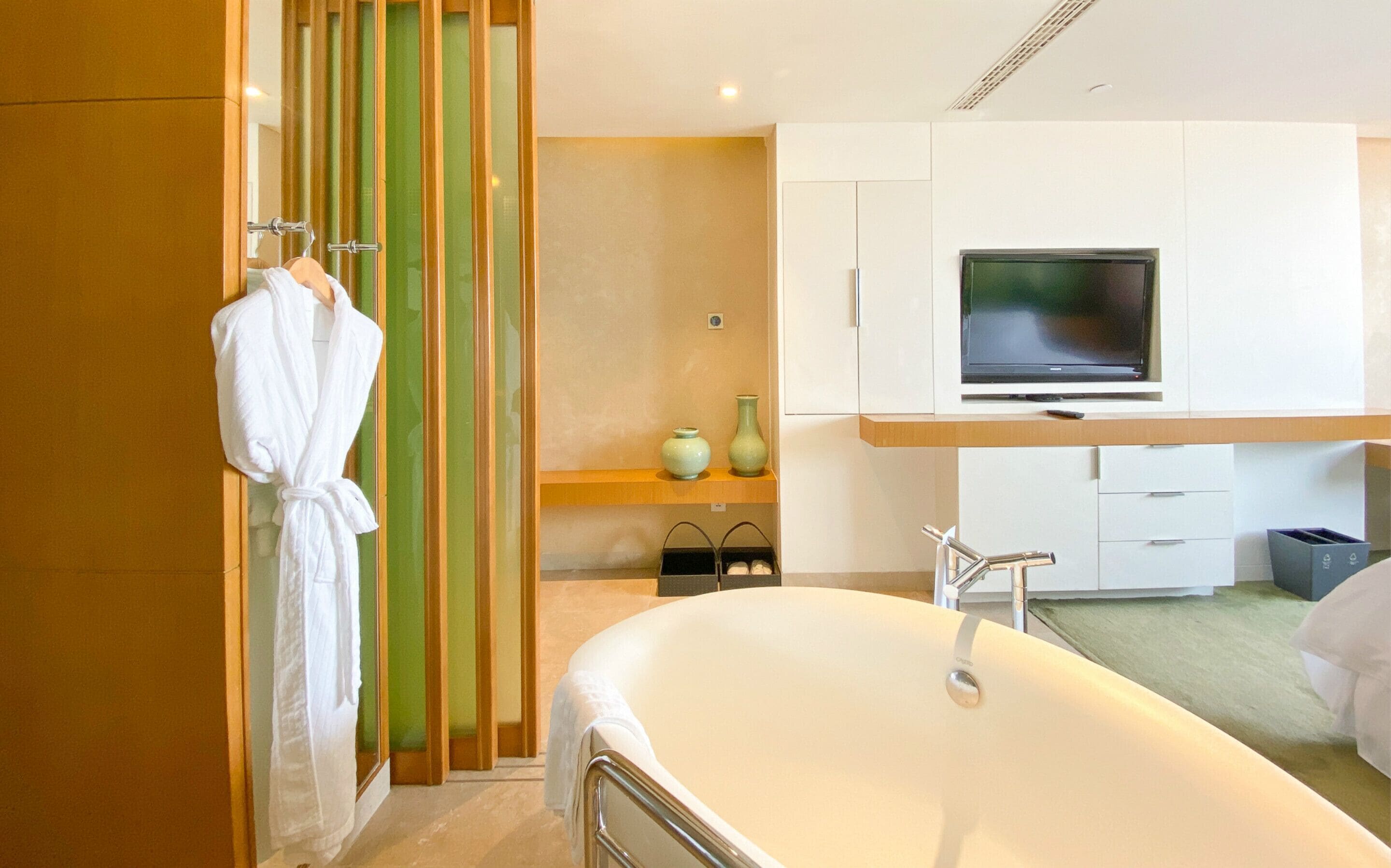 Un baño moderno con una bañera grande, un tocador con televisión y un perchero para abrigos.