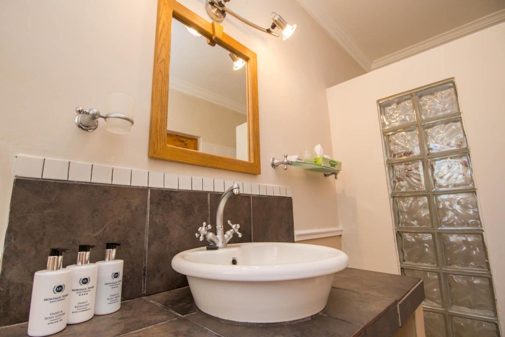 A bathroom with a white sink, a wooden-framed mirror, and a glass shower enclosure.