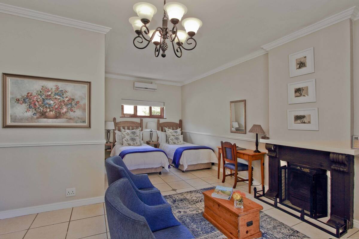 Een ruime woonkamer met een open haard, een bank, een salontafel en een schilderij aan de muur.