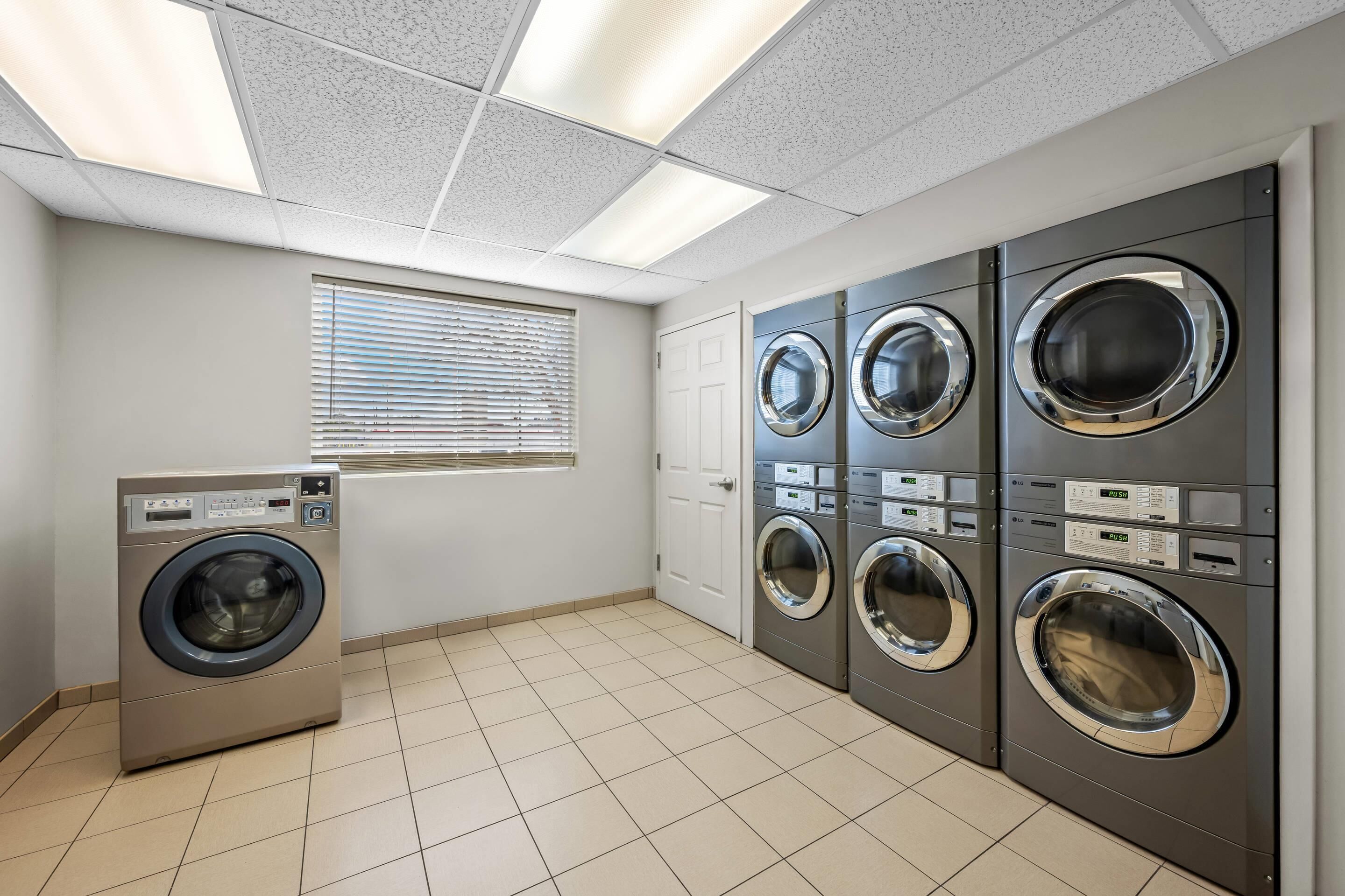 A laundry room with a single front-loading washing machine, a dryer, and a stacked washer-dryer unit.