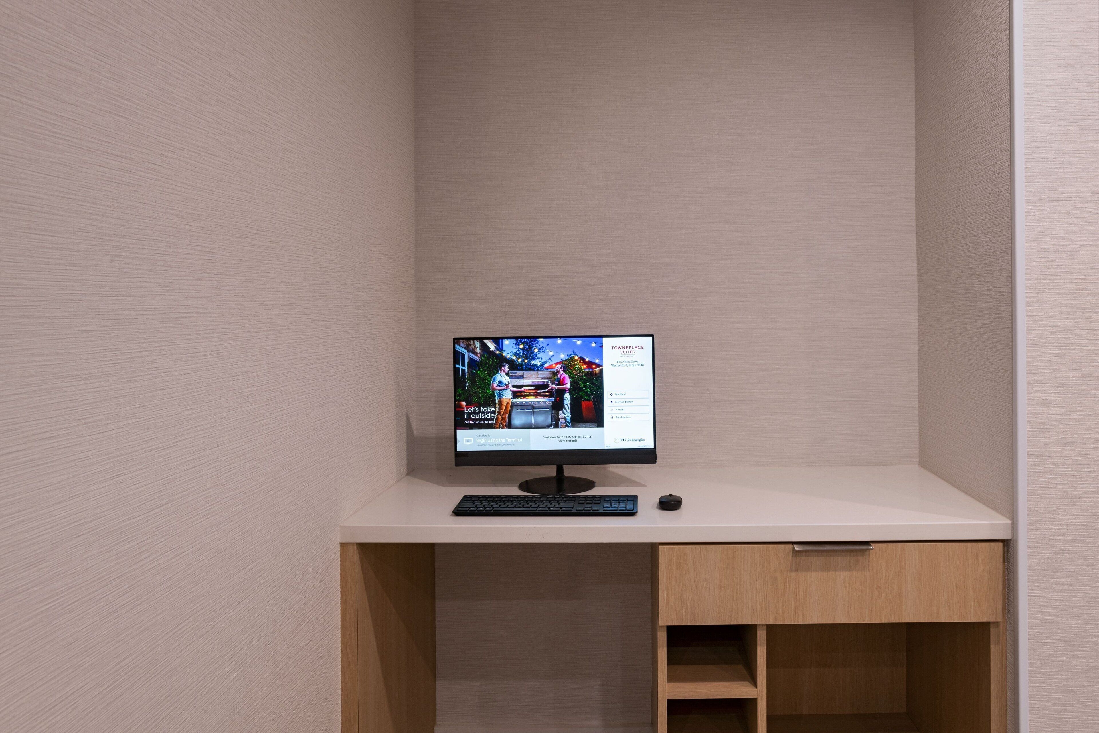 A computer monitor on a white desk with a keyboard and a mouse.