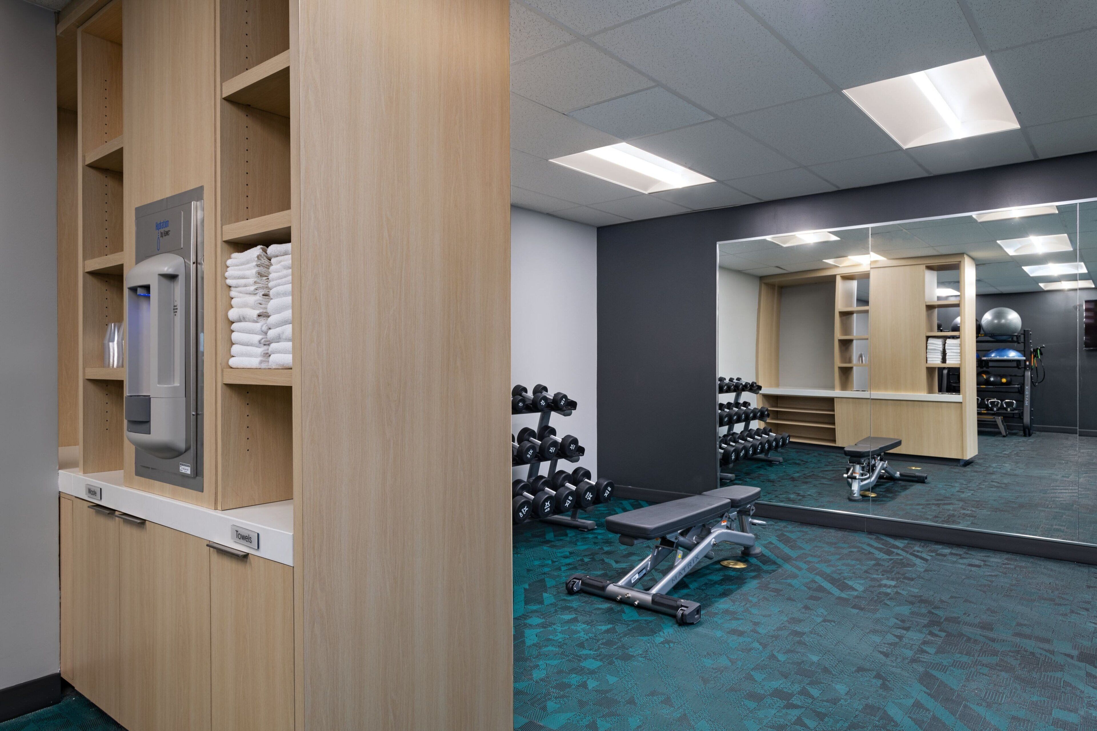 A gym with wooden lockers, a water dispenser, and various exercise equipment.