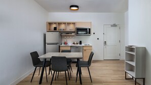 Una cucina compatta con tavolo, sedie, forno a microonde e frigorifero.
