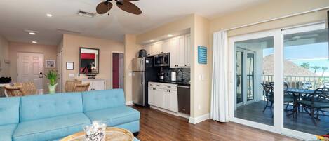 A spacious living room with a blue sofa, a wooden coffee table, and a ceiling fan.