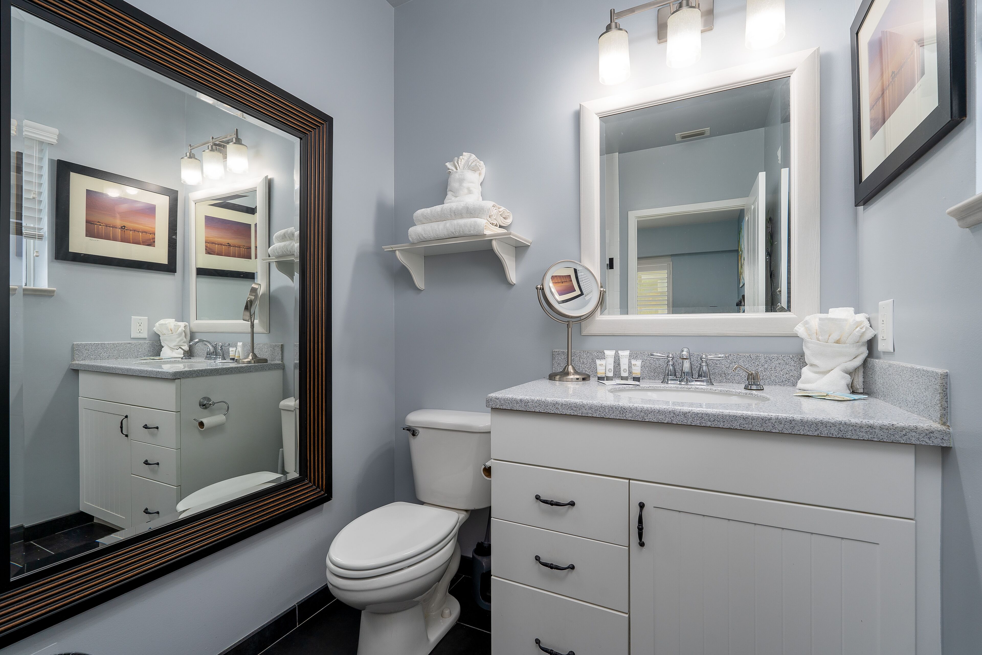 A bathroom with a white toilet, a sink with a mirror, and a towel rack.