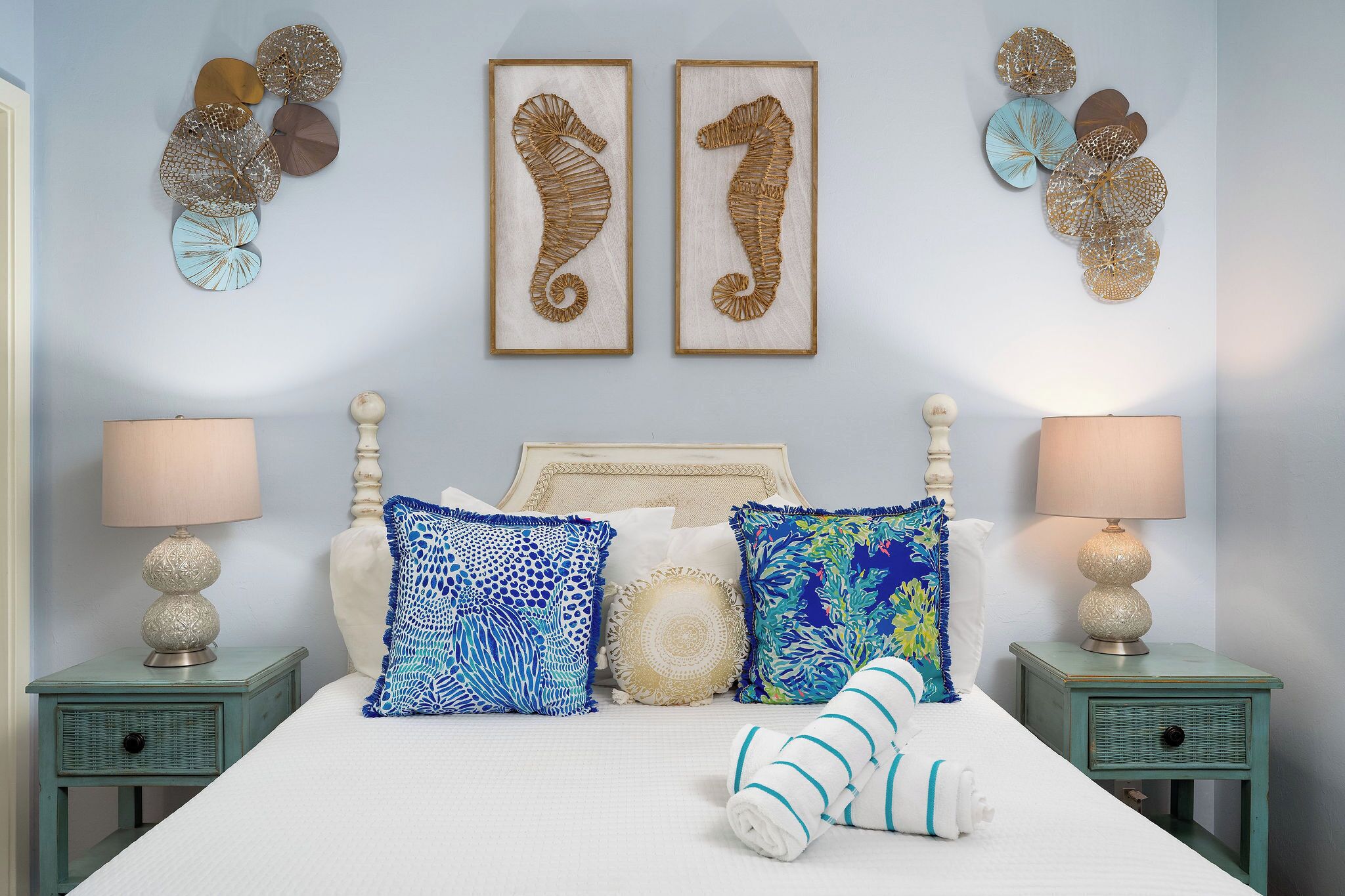 A bedroom with a bed, two nightstands, decorative wall art, and a lamp.