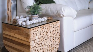 En hvid sofa med et grønt pled, et træsidebord med en plante, og en væg med palme-motiver.