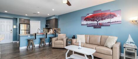 A modern living room with a beige sofa, a white coffee table, and a ceiling fan.