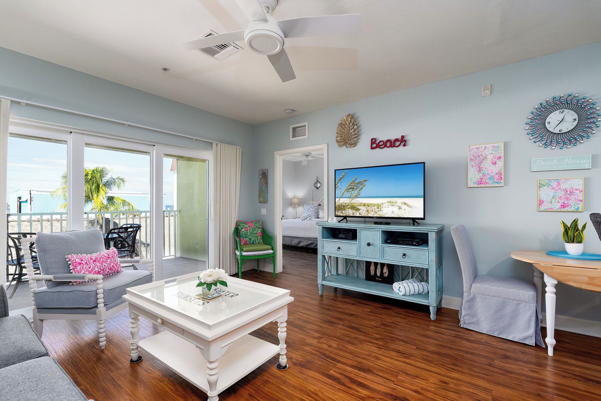 A spacious living room with a television, a coffee table, and a balcony with a view.
