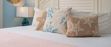 A bed with a white headboard, a blue wall, and a decorative shell on the wall.