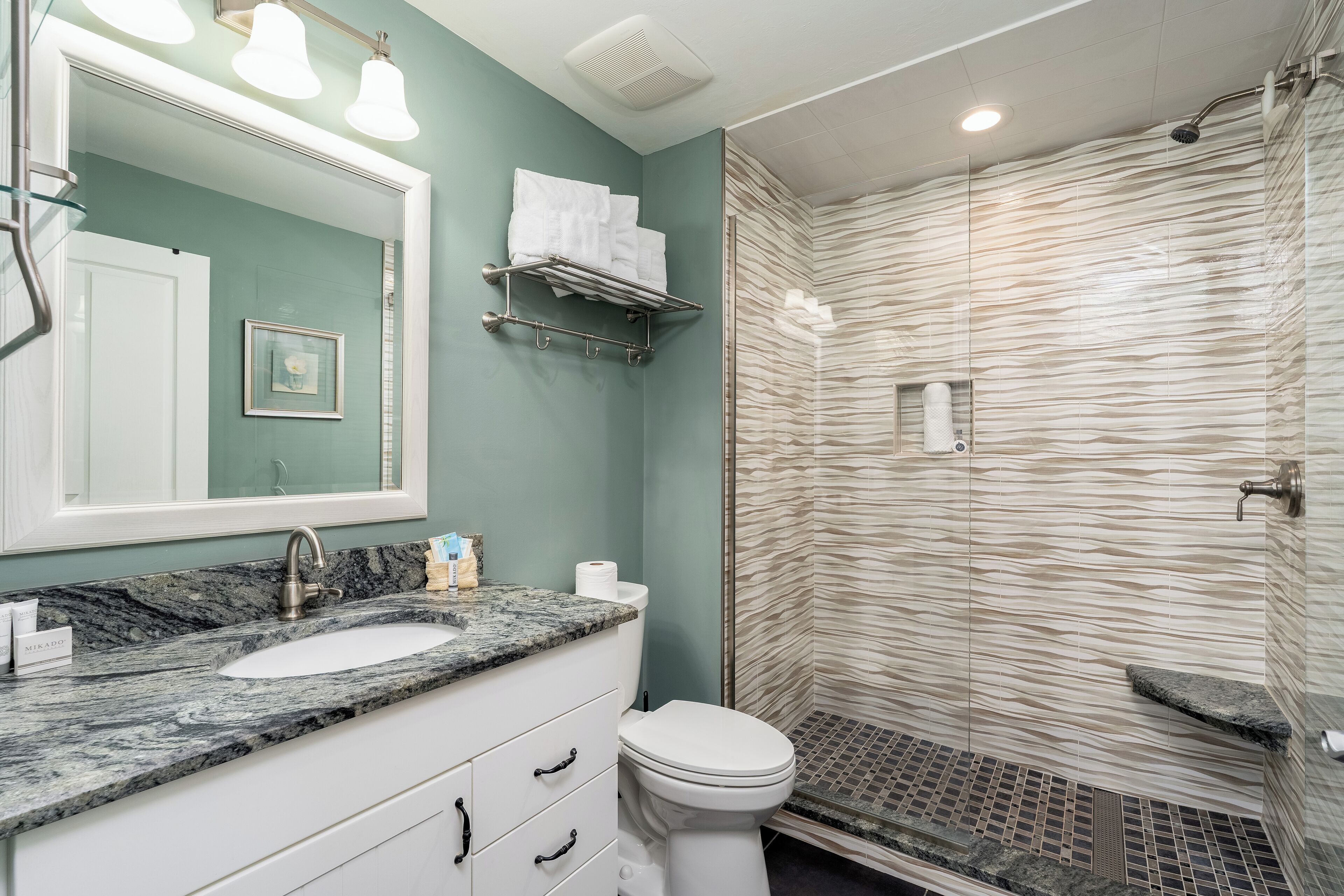 A bathroom with a marble sink, a toilet, a shower with a glass door, and a towel rack.