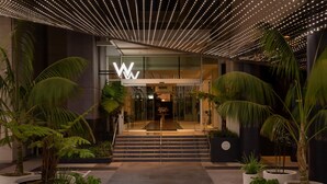 A modern building entrance with a prominent 'W' logo, surrounded by large potted plants and a patterned ceiling. - W Hollywood (Los Angeles)