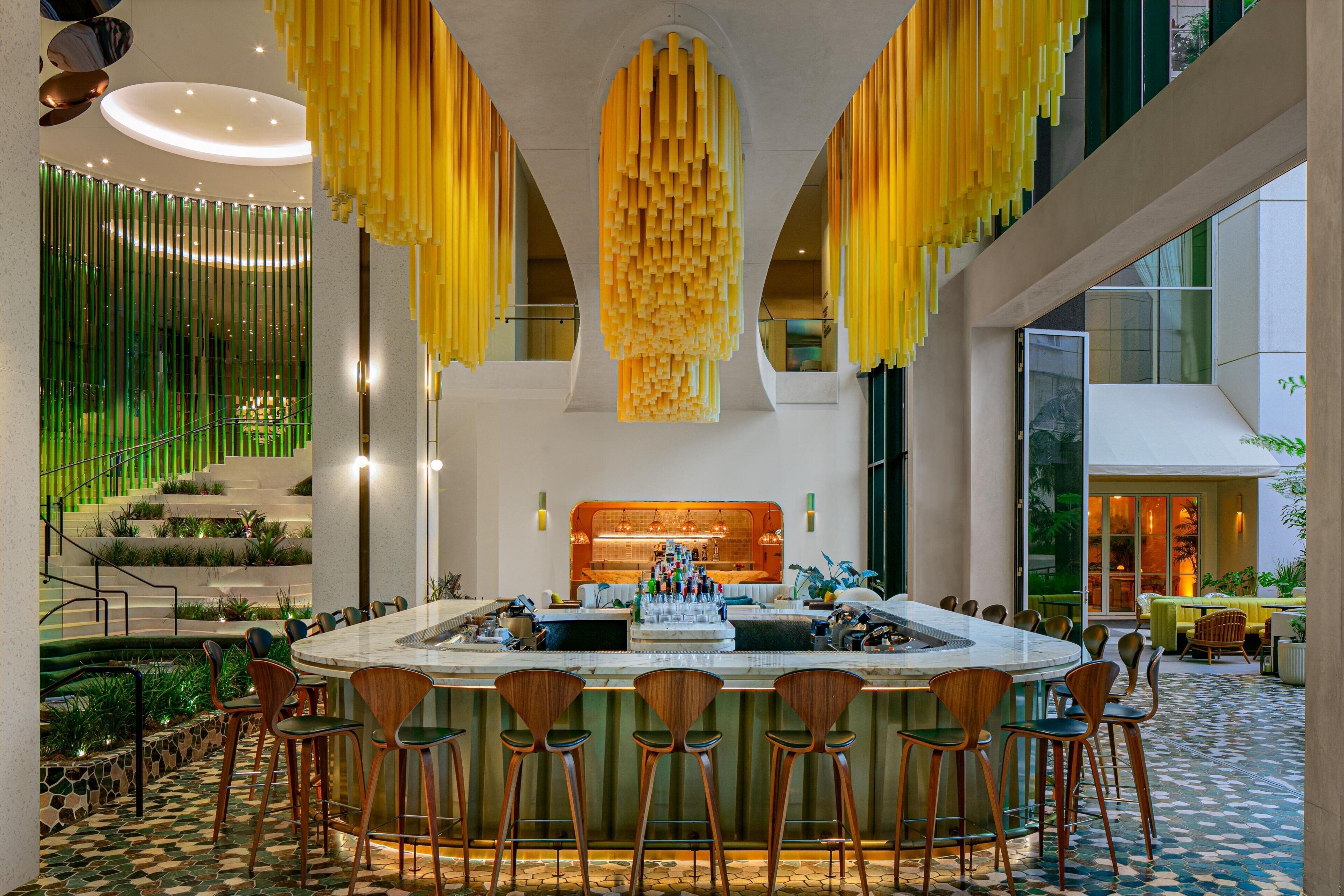 A modern bar area with a central bar, multiple stools, and a decorative hanging element.