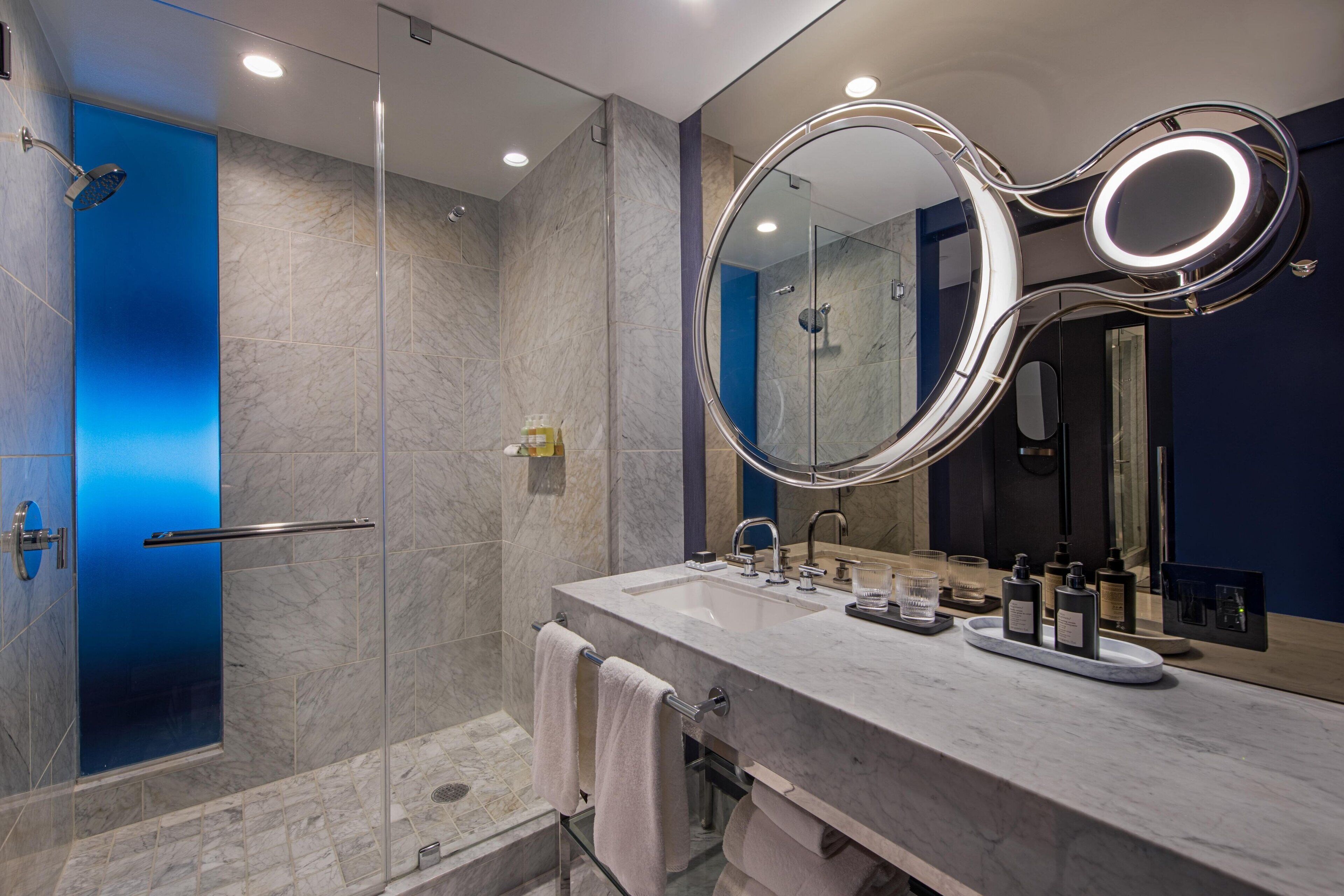 Un baño moderno con ducha de vidrio, tocador de mármol y un perchero para toallas.