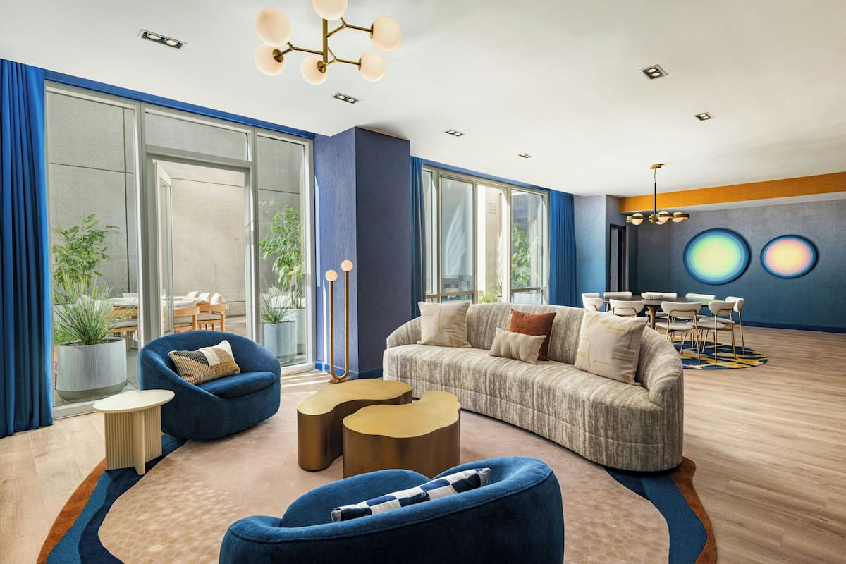 A modern living room with a sofa, armchairs, and a coffee table. There is a dining area with a table and chairs.