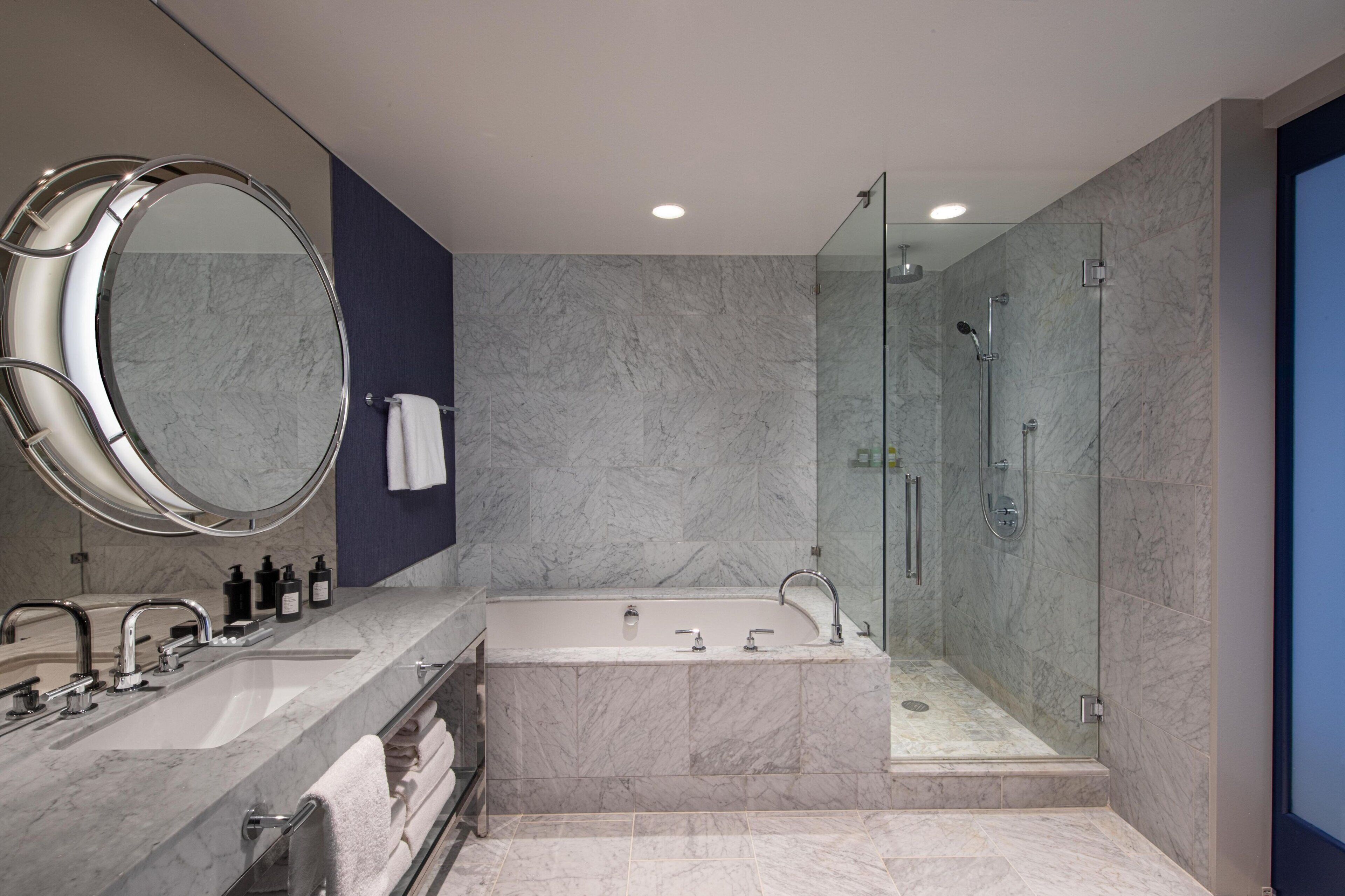 Un baño moderno con un espejo grande, una bañera, ducha y tocador con lavamanos.