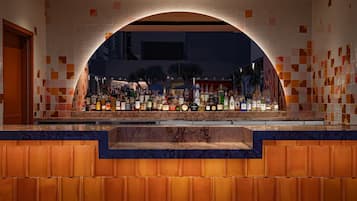 A bar area with a tiled archway, a variety of bottles, and a marble counter.