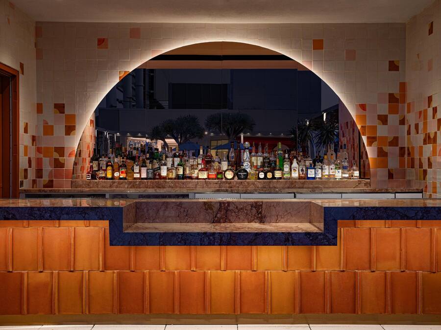 A bar area with a tiled archway, a variety of bottles, and a marble counter.