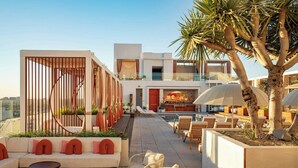 A rooftop lounge area with seating, a pool, and a bar. - W Hollywood (Los Angeles)